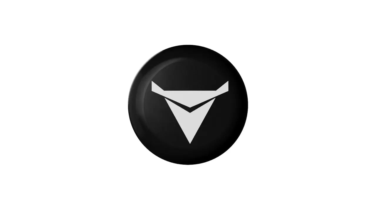 A black circular badge features a stylized gray V-shaped logo in the center, reminiscent of the Decibullz REPLACEMENT Single Back Plug. The logo consists of two intersecting triangles, with the top triangle pointing downwards and the bottom triangle pointing upwards. The background is plain white.