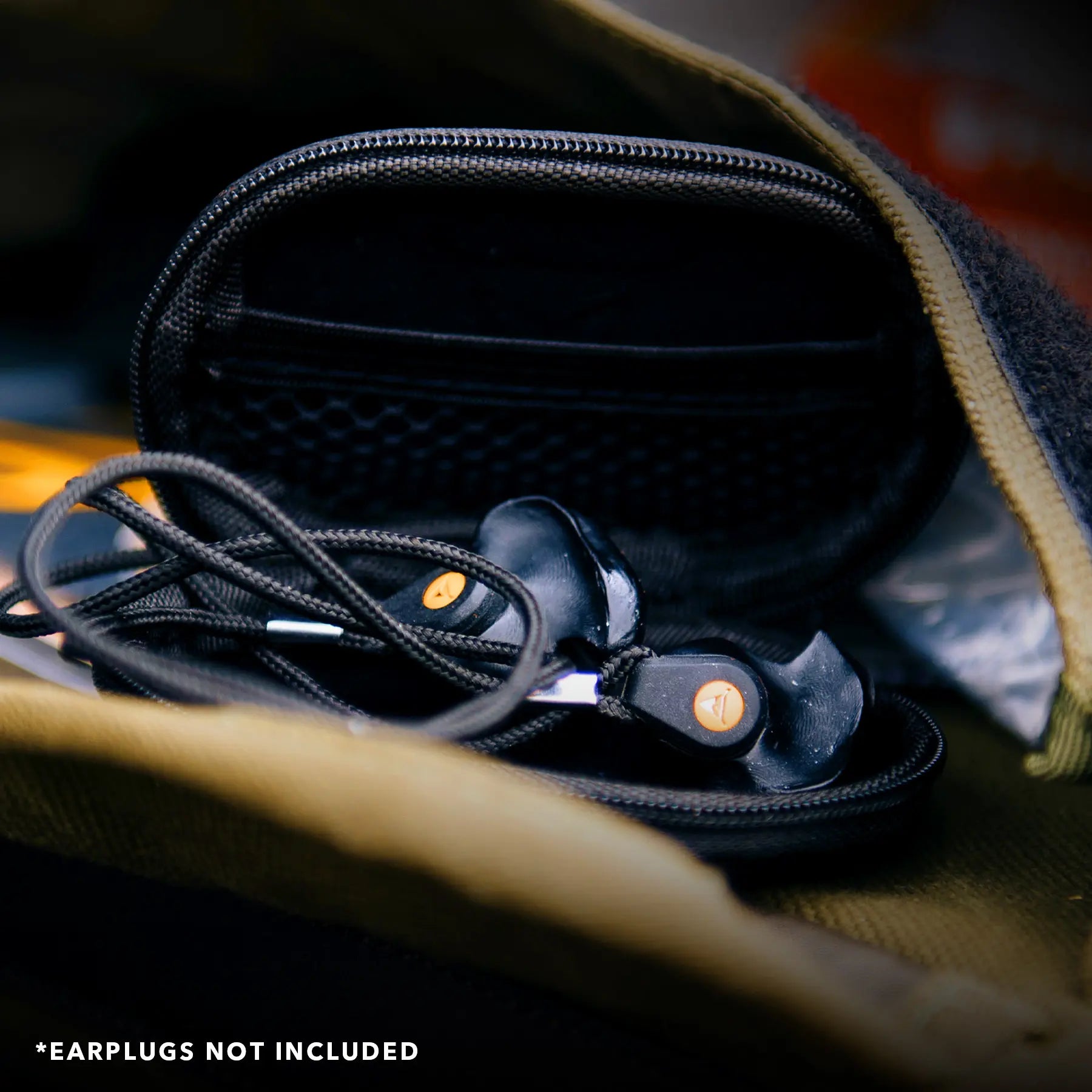 A Decibullz Premium Earplug and Earphone Carrying Case is open, revealing its contents. Black corded earplug covers with orange symbols are partially out of the case. The text at the bottom of the image reads "*EARPLUGS NOT INCLUDED.
