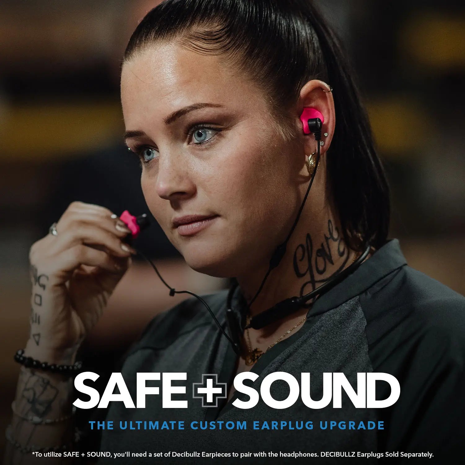 A woman with light-colored eyes and brown hair tied back is wearing pink earplugs with attached black wires, enhanced by noise suppression technology. She is looking to her left. Text at the bottom of the image reads "Decibullz SAFE + SOUND Wireless Headphone Conversion Kit The Ultimate Custom Earplug Upgrade.