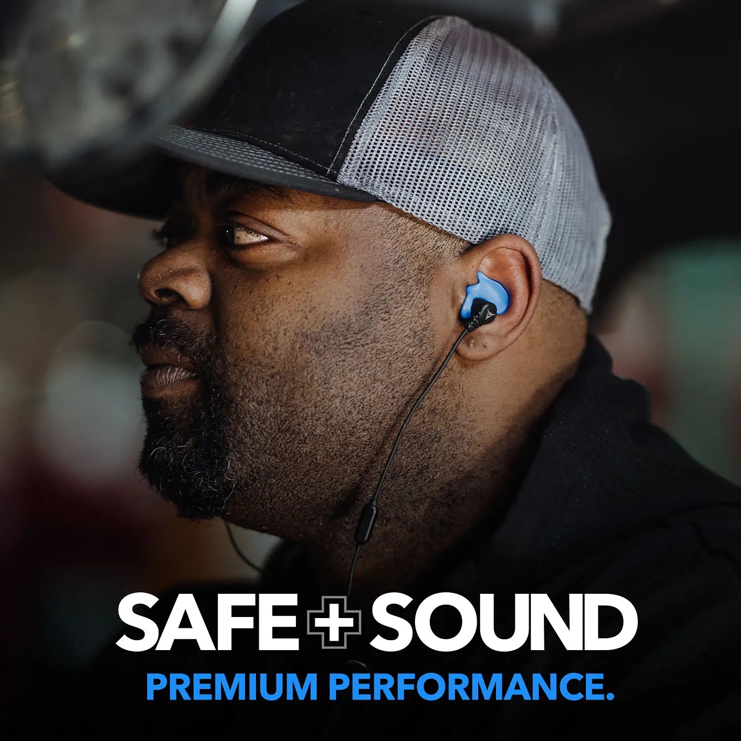 A man wearing a black shirt and a black and gray baseball cap is shown in close-up, donning blue earplugs with a thin black cord. The text "Decibullz SAFE + SOUND Custom Molded Bluetooth Wireless Earplug Headphones" is displayed at the bottom of the image, highlighting advanced noise suppression technology.